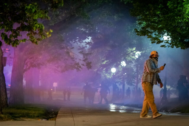 View through park of pedestrians in background.