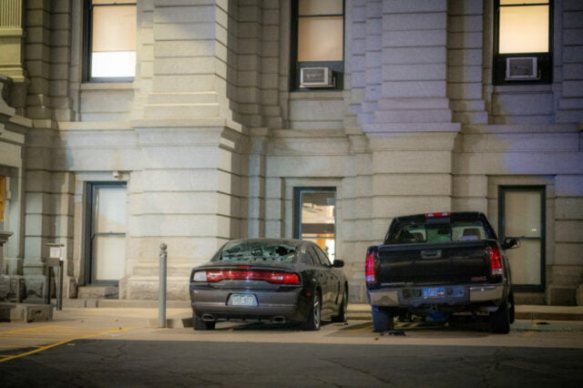 Two vandalized civilian cars parked outside of capitol building.