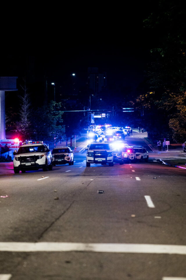 Seven police vehicles with their lights off approaching.