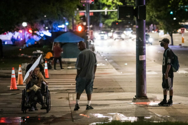 Night time on city sidewalk with protesters.