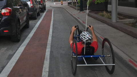 Recumbent cycylist approaches an intersection in the bike lane along side traffic