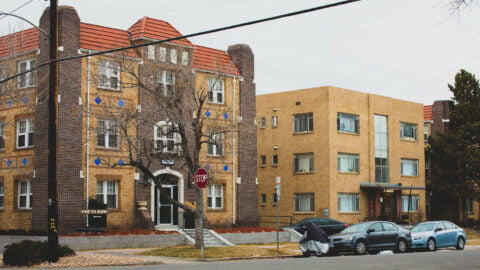 residential street with two apartment buildings. cars parked on the street. Trees are leafless, indicating late fall or winter