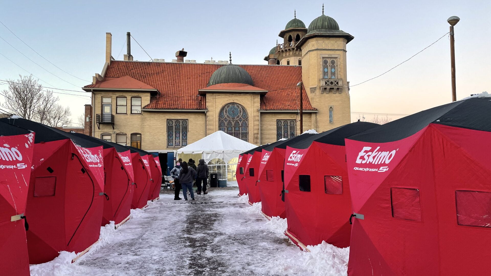 Red Arctic-grade tents line a snowy path leading toward Denver Community Church