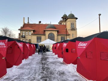 Red Arctic-grade tents line a snowy path leading toward Denver Community Church