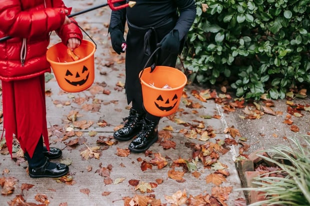 Two trick or treaters with jack-o-lantern buckets to store treats